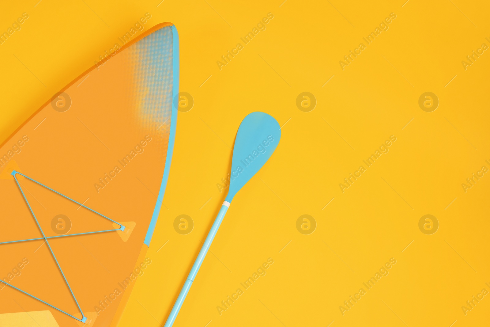 Photo of Board and paddle on orange background, flat lay with space for text. Standup paddleboarding (SUP)