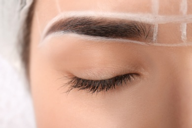 Young woman with marks on face before eyebrow permanent makeup procedure, closeup