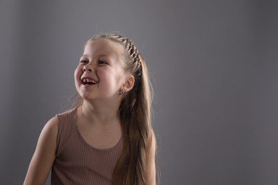 Photo of Little girl with braided hair on grey background. Space for text
