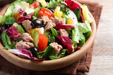 Photo of Bowl of delicious salad with canned tuna and vegetables on wooden table, closeup