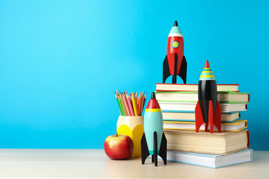 Bright toy rockets and school supplies on wooden table. Space for text