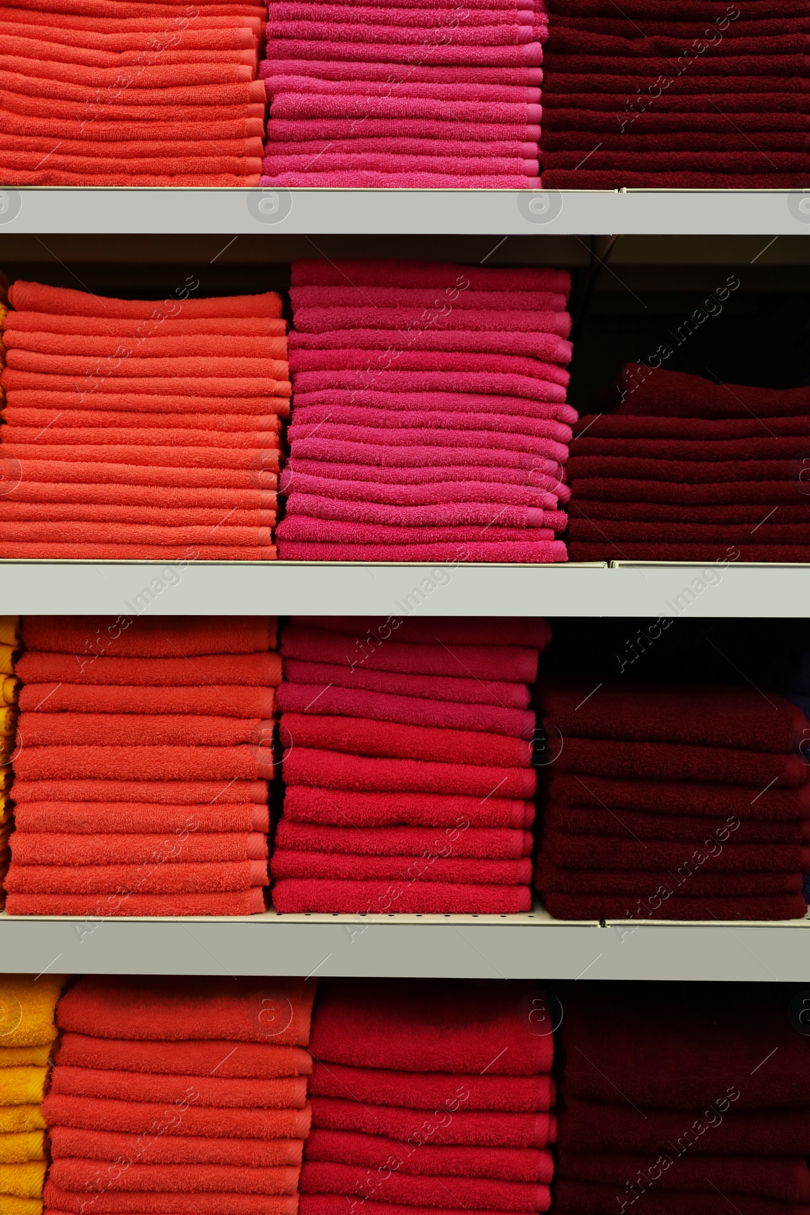 Photo of Stacks of colourful towels on store shelves