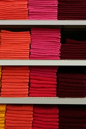 Photo of Stacks of colourful towels on store shelves