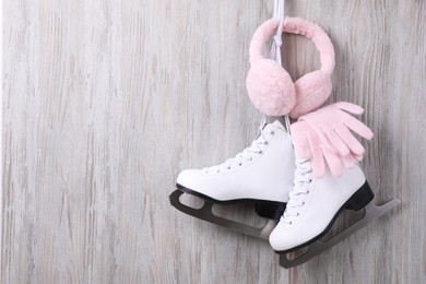 Photo of Pair of ice skates, warm earmuffs and gloves hanging on wooden wall, space for text