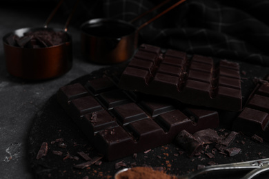 Photo of Tasty dark chocolate bars on black slate board