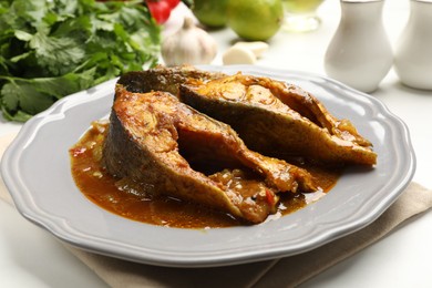 Photo of Tasty fish curry on white table, closeup. Indian cuisine