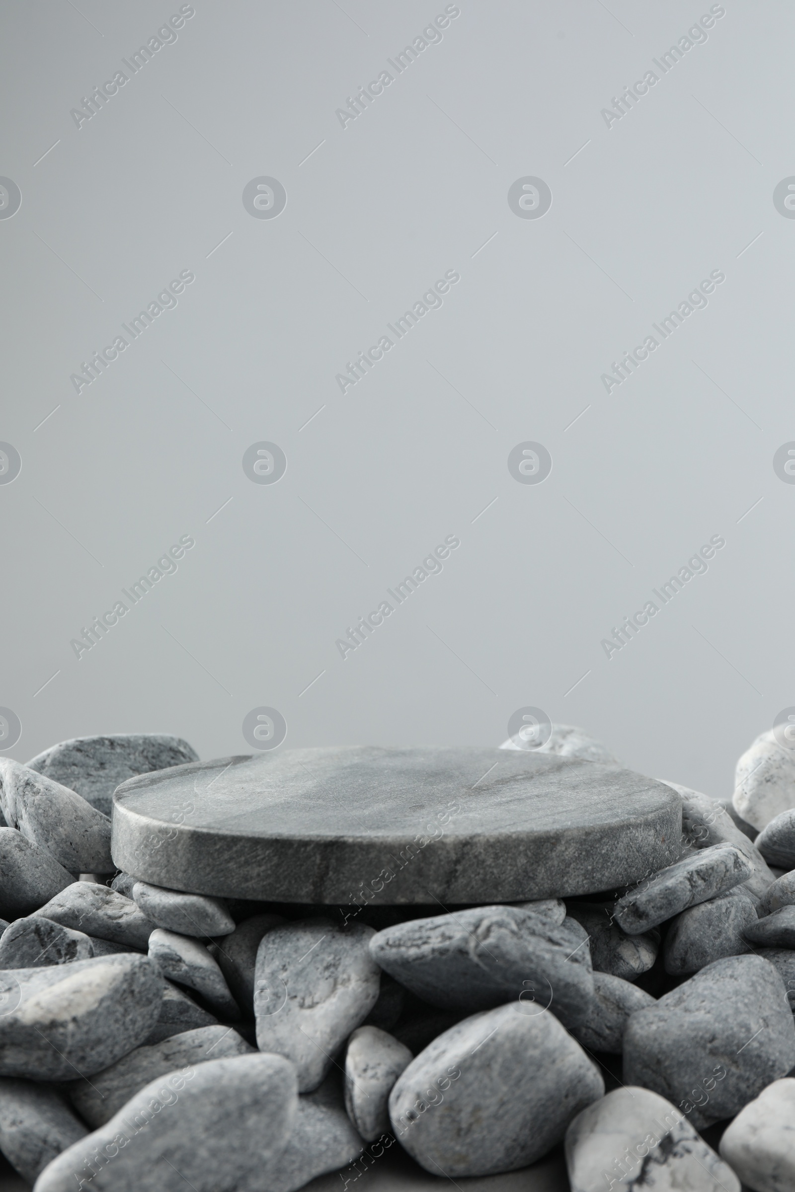 Photo of Presentation for product. Stone and pebbles on grey background. Space for text