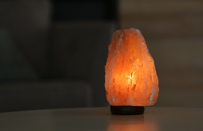 Photo of Himalayan salt lamp on table against blurred background