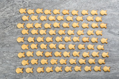 Delicious goldfish crackers on grey table, flat lay