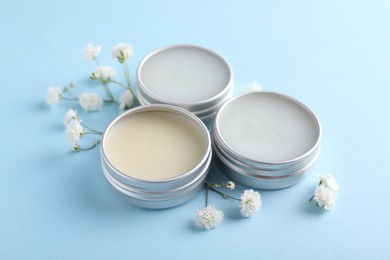 Different lip balms and gypsophila on light blue background