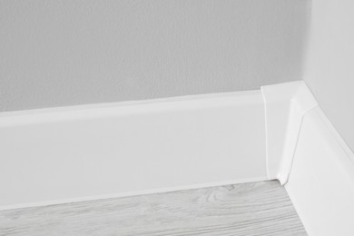 Photo of White plinth with connector on laminated floor near wall indoors, closeup