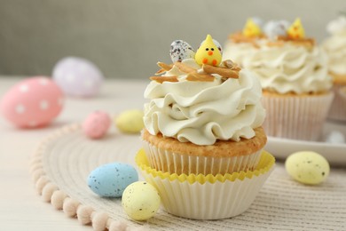 Photo of Tasty Easter cupcakes with vanilla cream and candies on table, closeup