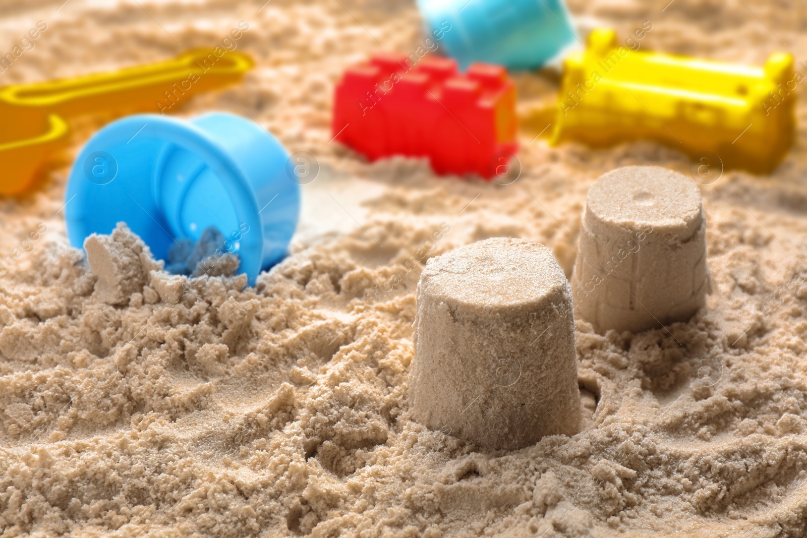 Photo of Little figures and beach toy set on sand. Outdoor play