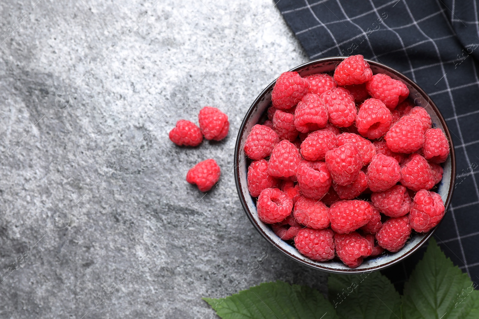 Photo of Delicious fresh ripe raspberries in bowl on grey table, flat lay. Space for text