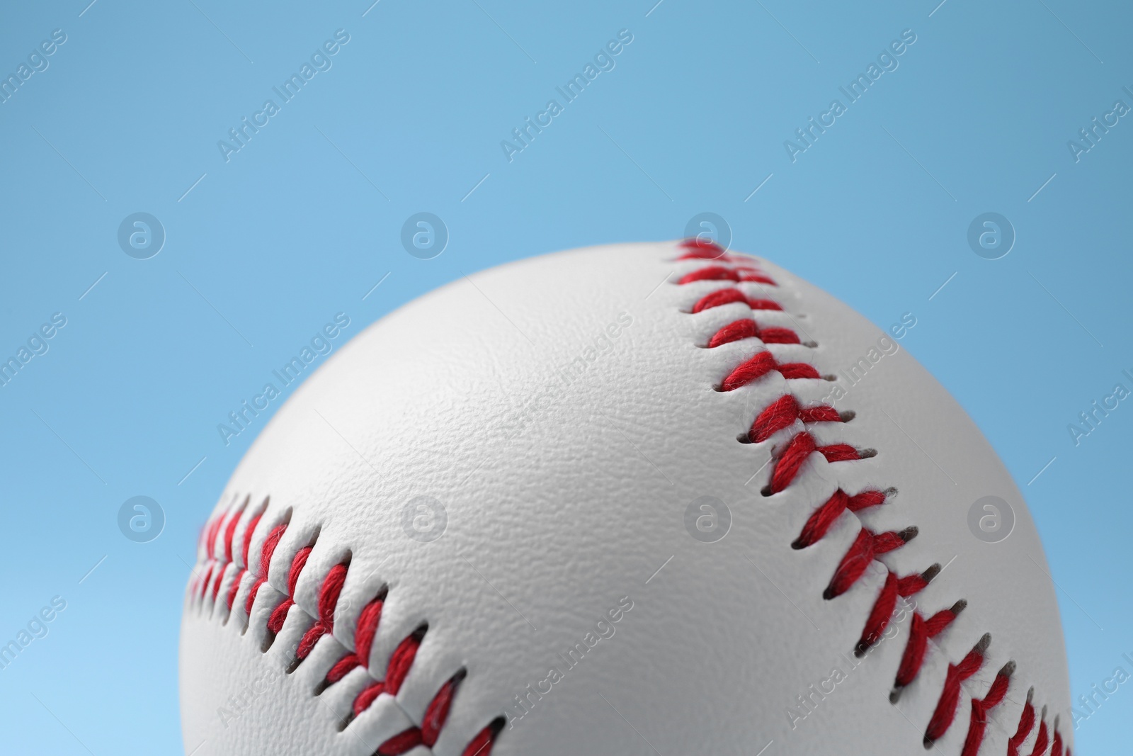 Photo of One baseball ball on light blue background, closeup