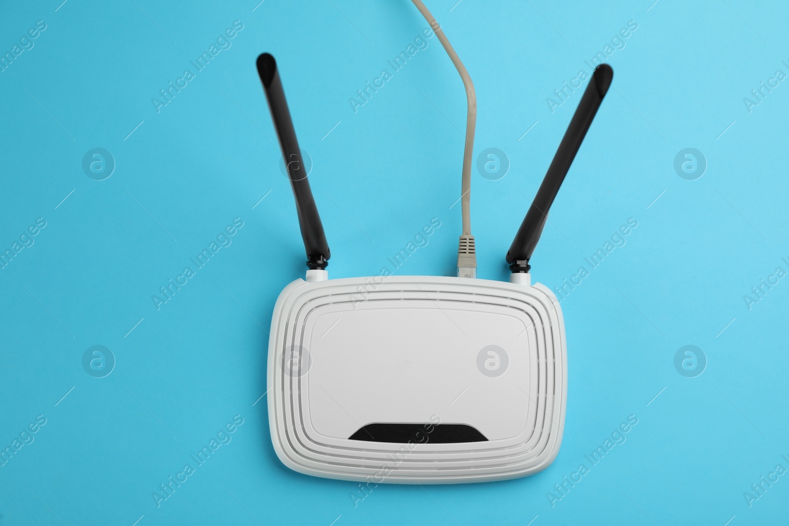 Photo of Modern Wi-Fi router on light blue background, top view