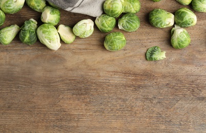 Fresh Brussels sprouts on wooden table, flat lay. Space for text