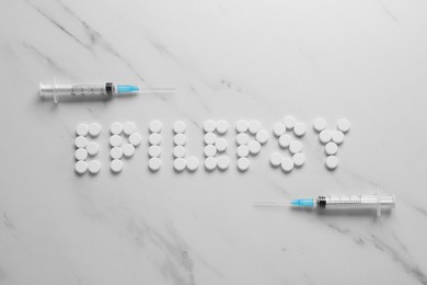Photo of Word Epilepsy made of pills and syringes on white marble table, flat lay