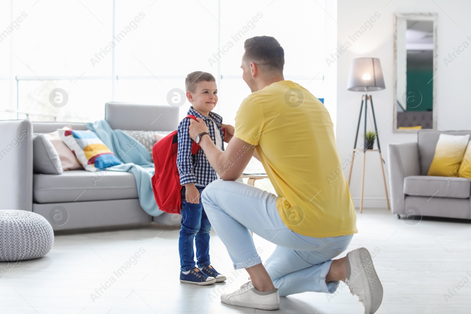 Photo of Young man helping his little child get ready for school at home