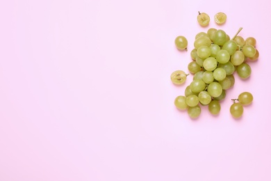 Photo of Bunch of ripe green grapes on pink background, flat lay. Space for text