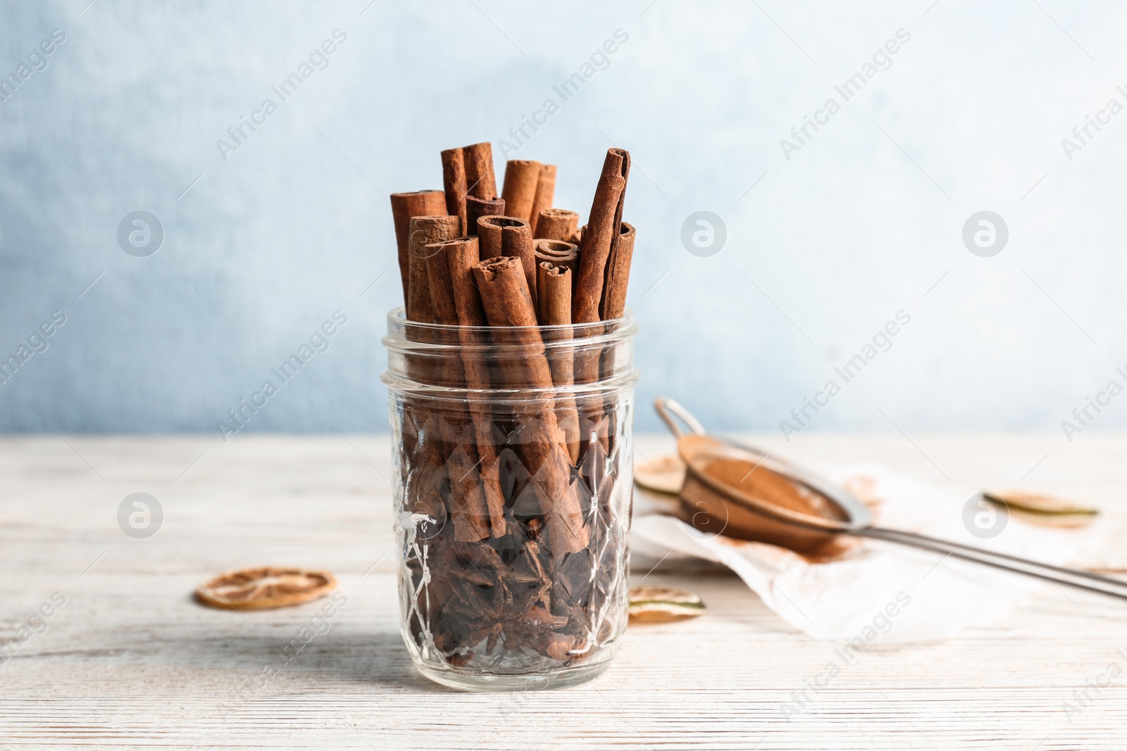Photo of Jar with aromatic cinnamon sticks on wooden table