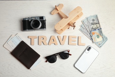 Flat lay composition with word TRAVEL, camera and passport on wooden background. Tourist agency