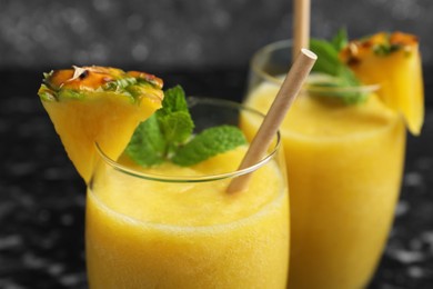 Tasty pineapple smoothie in glasses on blurred background, closeup
