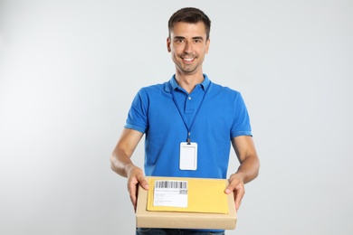 Photo of Happy young courier with parcel and envelope on white background