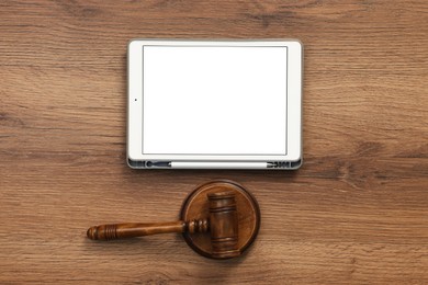 Photo of Modern tablet and gavel on wooden table, flat lay. Space for text