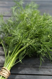 Photo of Bunch of fresh green dill on grey wooden table, closeup