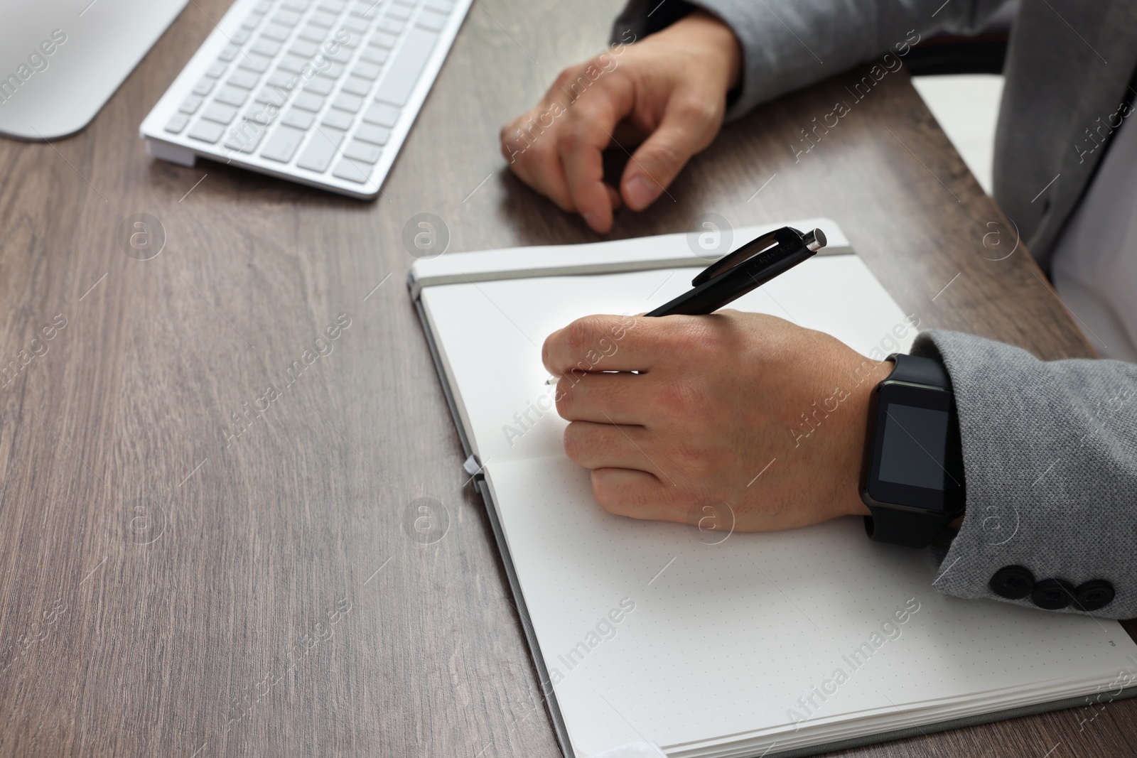 Photo of Boss writing in notebook at wooden table, closeup. Space for text