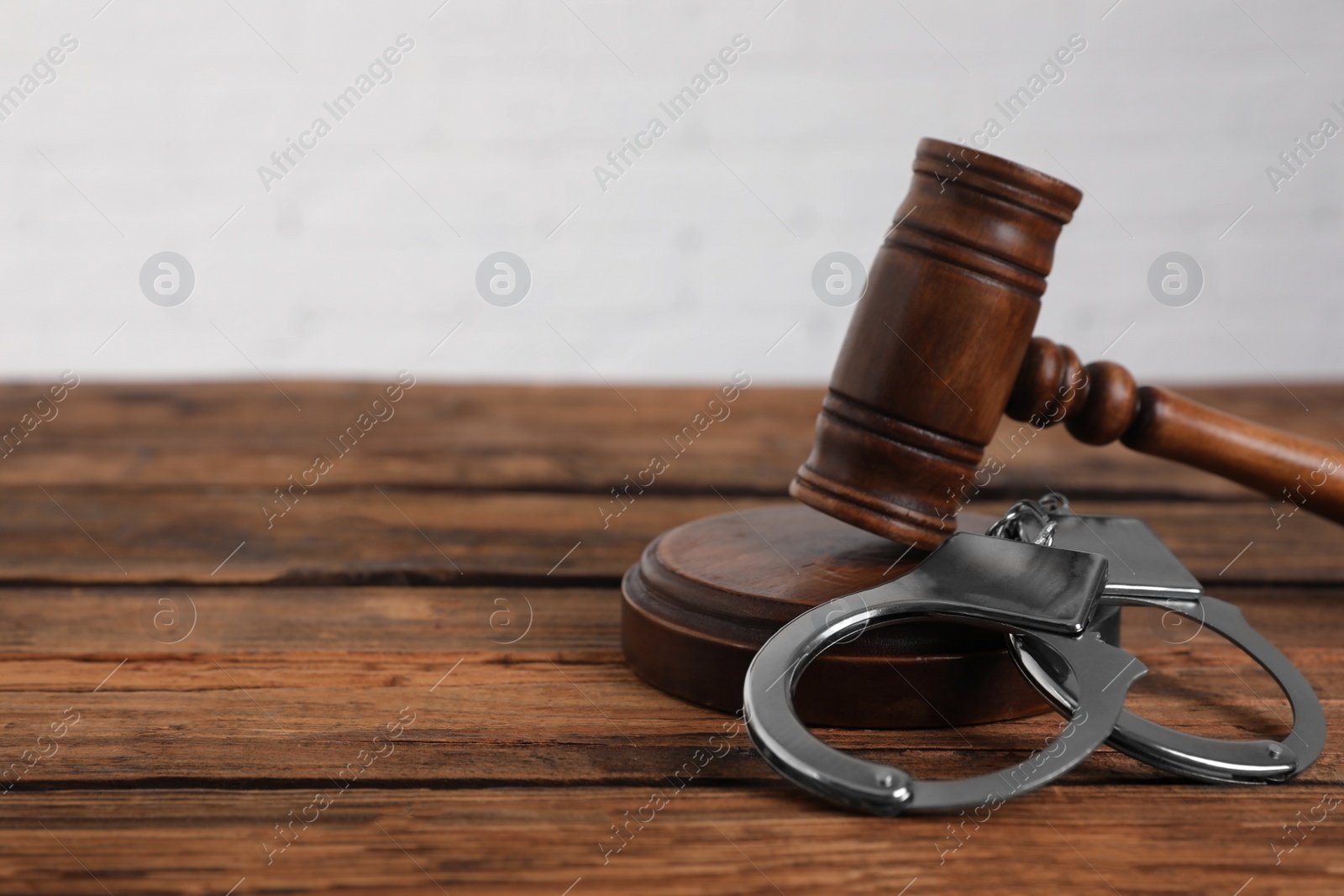 Photo of Gavel and handcuffs on wooden table, space for text. Criminal law