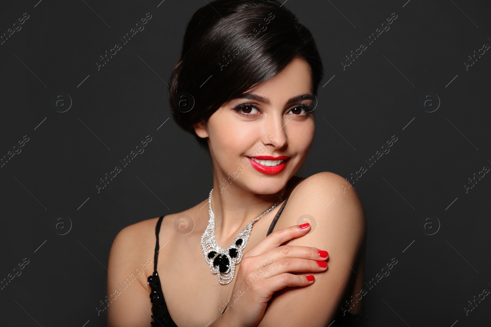 Photo of Beautiful young woman with elegant jewelry on dark background