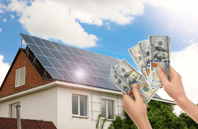 Image of Man counting money against house with installed solar panels. Renewable energy and money saving