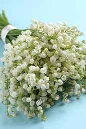 Beautiful lily of the valley bouquet on light blue background, closeup