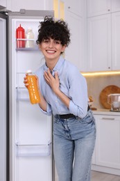 Photo of Smiling food blogger with bottle of juice in kitchen