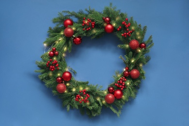 Photo of Beautiful Christmas wreath with festive decor on blue background, top view