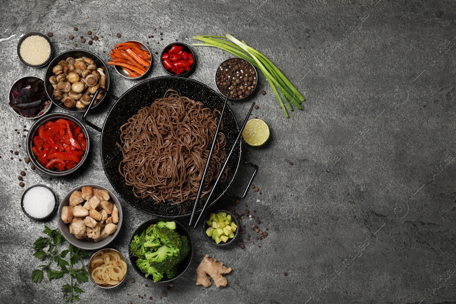 Photo of Wok with noodles, chicken and other products on grey table, flat lay. Space for text