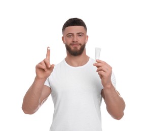 Photo of Handsome man with tube of body cream on white background