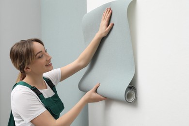 Photo of Worker hanging stylish wall paper sheet indoors