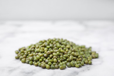 Photo of Pile of green mung beans on white marble table, closeup. Space for text