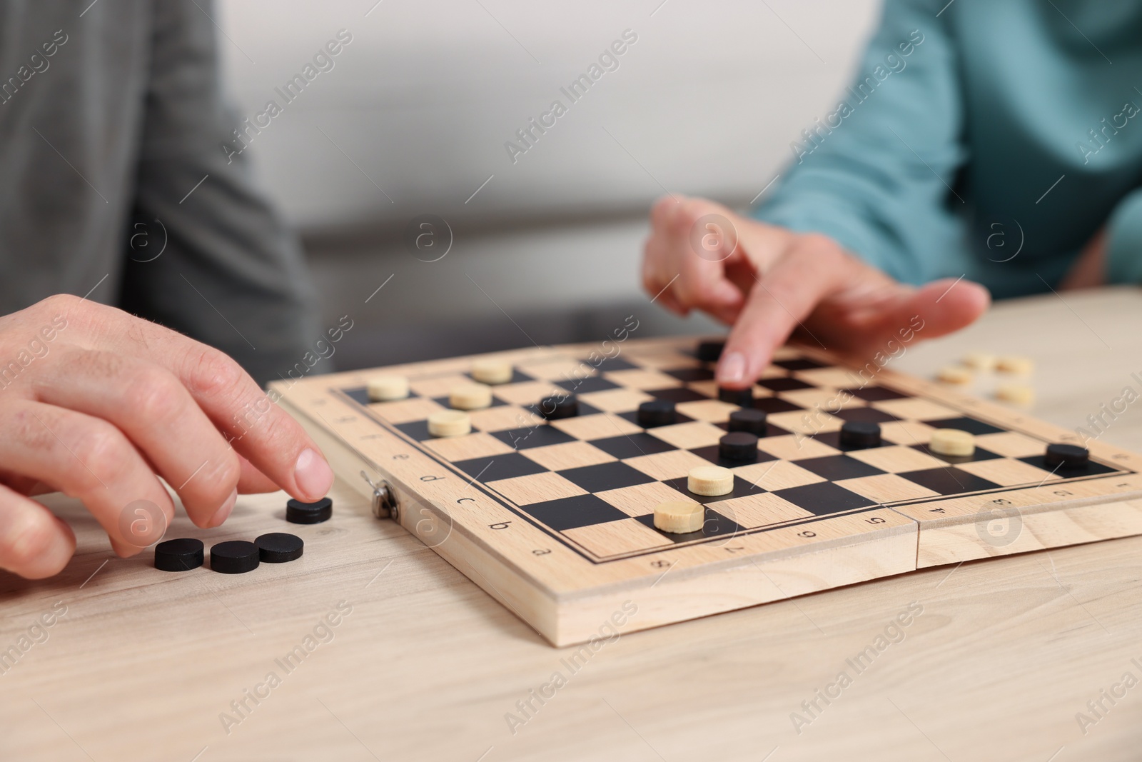 Photo of People playing checkers at wooden table, closeup