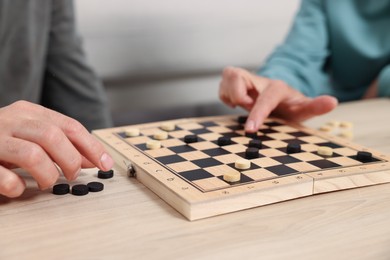 Photo of People playing checkers at wooden table, closeup
