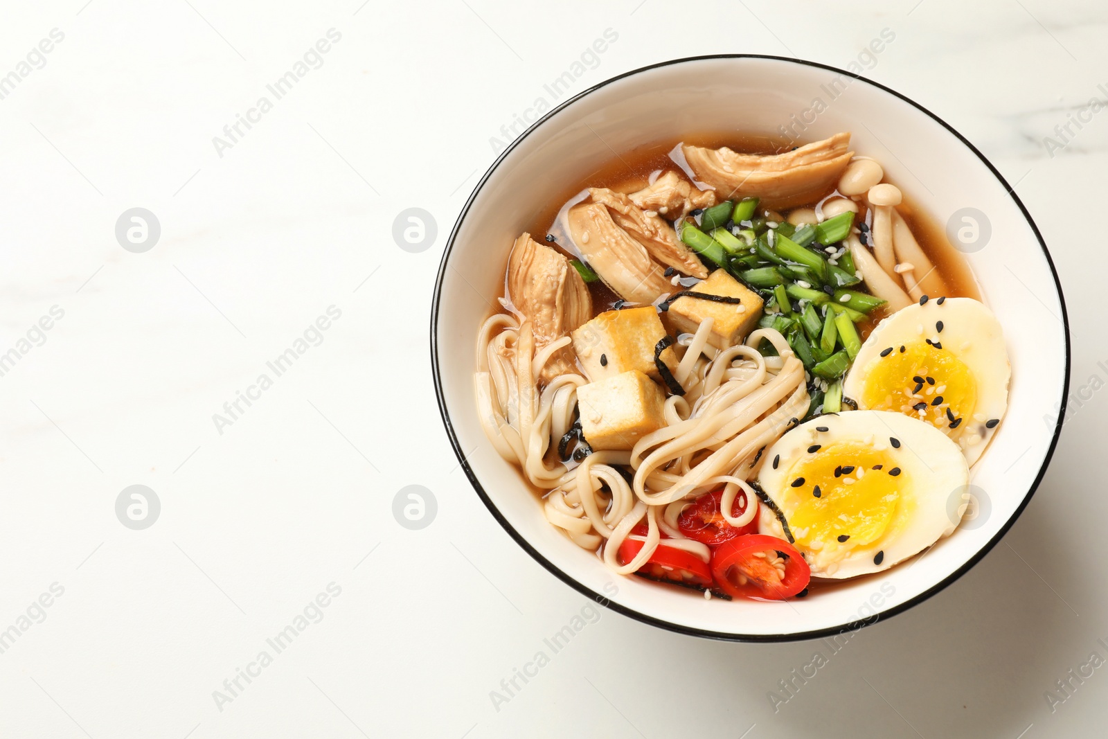 Photo of Bowl of delicious ramen on white marble table, above view. Noodle soup