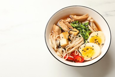 Photo of Bowl of delicious ramen on white marble table, above view. Noodle soup