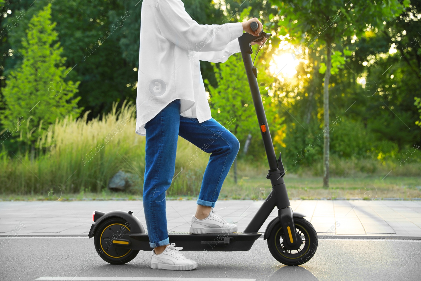 Photo of Woman with modern electric kick scooter in park, closeup