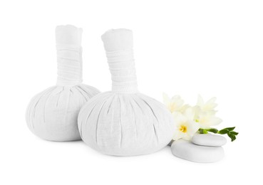 Photo of Herbal massage bags, flowers and spa stones on white background