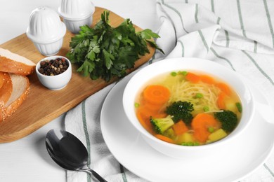 Photo of Delicious vegetable soup with noodles served on white wooden table