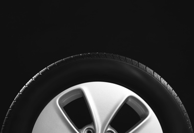 Car tire with rim on black background, closeup