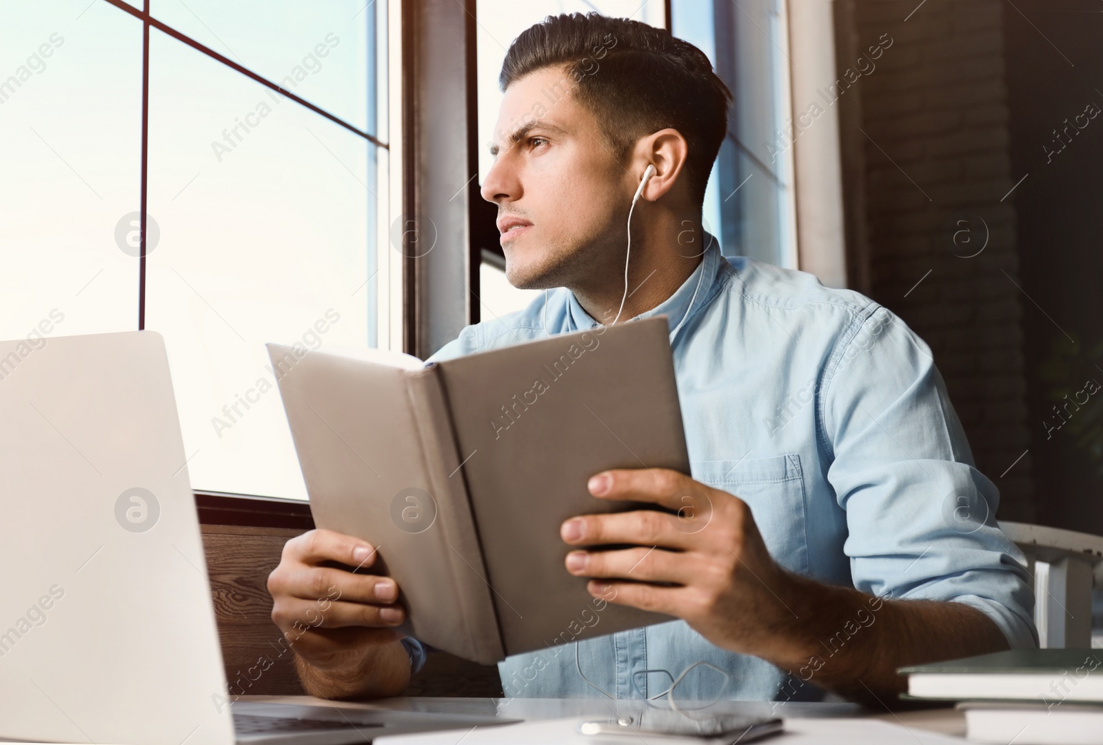 Photo of Man listening to audiobook at table in cafe